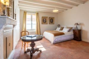 a bedroom with a bed and a table and a fireplace at Clos Chartrain in La Chartre-sur-le-Loir