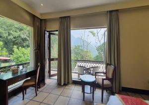 a room with a desk and a table and a large window at Aureva Shaantam Resorts & Spa - Rishikesh in Rishīkesh
