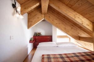 a bedroom with an attic with a bed and wooden ceilings at LA PULCE INNEVATA - Mansarda a due passi dal cielo - Dolomiti Affitti in Passo Rolle