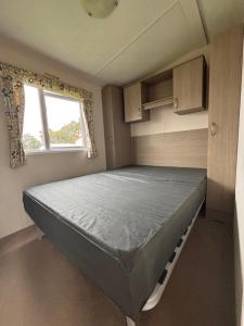 a bed in a small room with a window at Camping le quinquis in Clohars-Carnoët