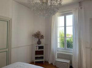 a bedroom with a chandelier and a bed and a window at Large house - Garden pool in Cognac
