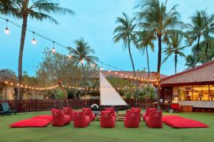 a group of red chairs on a lawn with palm trees at Paradisus by Meliá Bali in Nusa Dua