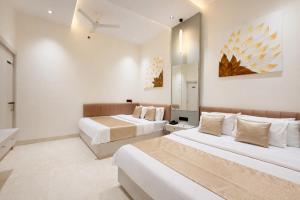 a hotel room with two beds and a mirror at Sharda Grand in Ujjain