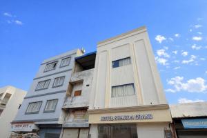 a tall white building with a sign on it at Sharda Grand in Ujjain