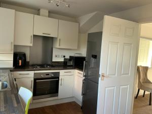a kitchen with white cabinets and a black refrigerator at Home away from away in Dartford