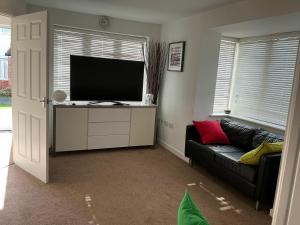 a living room with a black couch and a flat screen tv at Home away from away in Dartford