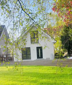a white house with yellow windows and green grass at Rhubarb Cottage in Navan