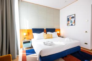 a bedroom with a large white bed with blue accents at voco Parma & Congressi by IHG in Parma +207 photos