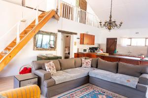 a living room with a couch and a staircase at Whitehouse- Hot Tub in Elands Bay