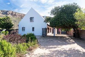 a white house with a triangular roof on a street at Whitehouse- Hot Tub in Elands Bay
