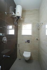 a bathroom with a toilet and a shower and a window at Radial Serviced Apartments in Chennai