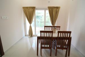 a dining room with a table and chairs and a window at Radial Serviced Apartments in Chennai +4 photos