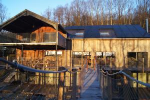 a large wooden building with a fence in front of it at Gîte DDS - Bridge into nature! in Manhay