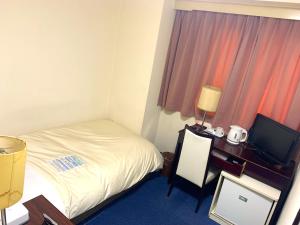 a hotel room with a bed and a desk with a television at Hotel Sunshine Iwaki in Iwaki