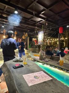 a group of people standing around a table next to a pool at Loopmoto Riverside Homestay in Làng Lap