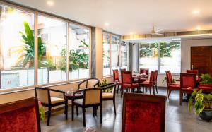 a restaurant with tables and chairs and large windows at Cana Boutique Stay in Porvorim