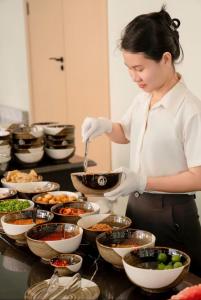 a woman in a kitchen preparing food in bowls at H- Dragon Hotel in Ðố Sơn