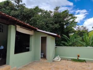 a green house with a white fence and trees at Chácara Angola in Andradas