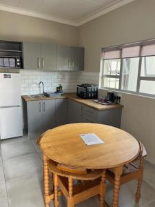 eine Küche mit einem Holztisch und einem kleinen Tisch mit Stühlen in der Unterkunft Anas Inn in Walvis Bay