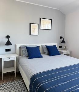 a bedroom with a bed with blue sheets and two tables at Morza Szum in Dziwnów