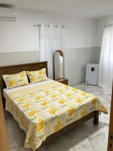 a bedroom with a bed with a yellow and white blanket at Hotel Pirâmide in Igreja