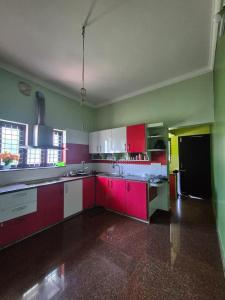 a kitchen with red and green walls and white cabinets at meadowell homestay in Kizhake Chālakudi
