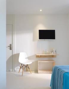 a white room with a chair and a tv on the wall at Hotel Eolo in Port de Pollensa