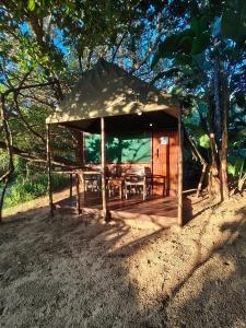 a wooden gazebo with a table and chairs at Amangwane Tented Camp in Kosi Bay
