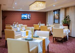 a restaurant with white tables and chairs and a tv at Grand Legacy Hotel in Kigali