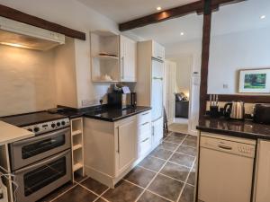 a kitchen with white cabinets and black counter tops at A River Runs By in Staveley