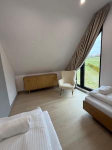 a bedroom with a bed and a chair and a window at Stodoły pod Łysą Górą in Huta Szklana