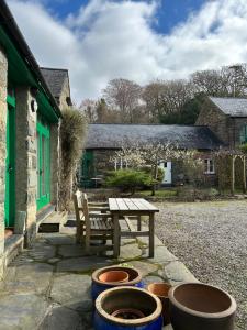 a picnic table and some pots in front of a house at Y Stwdio, Ferm Glandwr in Barmouth