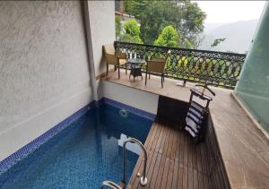 a balcony with a pool with chairs and a table at Aureva Shaantam Resorts & Spa - Rishikesh in Rishīkesh