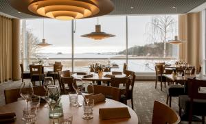 a restaurant with tables and chairs and a large window at Ruissalo Spa Hotel in Turku