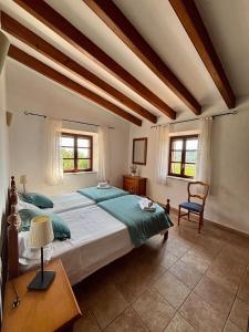 a bedroom with a large bed and two windows at Finca Es Puig, rustic estate with views in Es Carritxo +38 photos