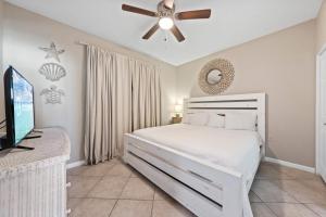 a bedroom with a white bed and a ceiling fan at Beach Club 1109 D in Gulf Shores