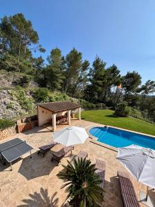 a swimming pool with chairs and umbrellas next to at Finca Es Puig, rustic estate with views in Es Carritxo