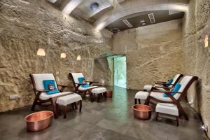 a group of chairs in a room with a stone wall at Palazzo Consiglia - IK Collection in Valletta