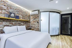 a bedroom with a white bed and a brick wall at 렉시호텔 in Seoul