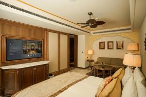 a bedroom with a bed and a flat screen tv at The Leela Palace Jaipur in Jaipur +140 photos