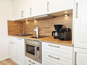 a kitchen with white cabinets and a sink and a microwave at Sonne, Wind und Meer in Westerland