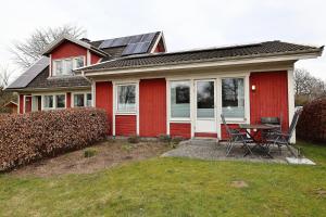 a red house with a table and chairs in the yard at Schwedenhaus Westensee 1 EG in Groß Vollstedt +2 photos