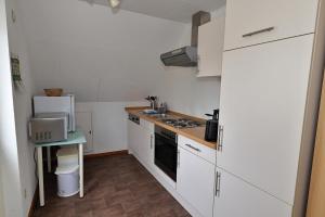 a small kitchen with white cabinets and a table at Schwedenhaus Westensee 2 OG in Groß Vollstedt