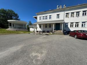 a red car parked in front of a white building at Åsen Apartment, Stamsund in Stamsund