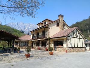 a large house with mountains in the background at Hotel El Jisu in Camaleño