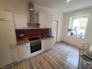 a kitchen with white cabinets and a sink at Ferienwohnung Alte Fleischerei in Lauchhammer