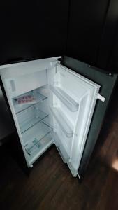 an empty refrigerator with its door open on a wooden floor at Centrum apartman s parkovaním in Trenčín