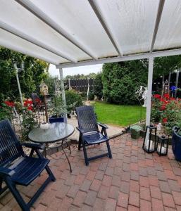 a patio with two chairs and a table under a white canopy at Sonnenhaus in Neuenkirchen +4 photos