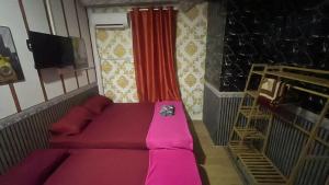 a room with a pink bed and a tv at CZ CLASSIC in Pasir Puteh