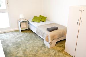 a white bedroom with a bed with green pillows at Hostel Września in Września